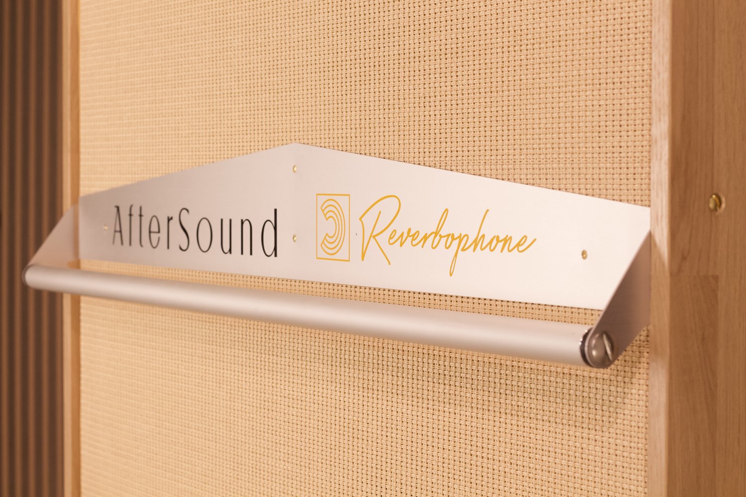 Macro detail of the aluminium AfterSound and Reverbophone sign on a blond grille weave