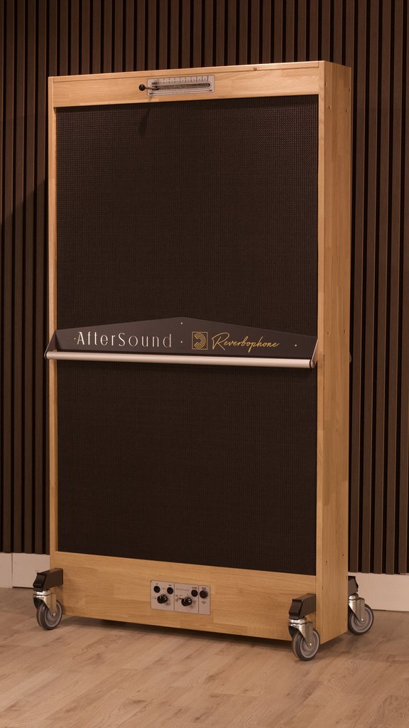 Reverbophone in a honey oak frame with a black grille, standing on castors against a slatted timber wall