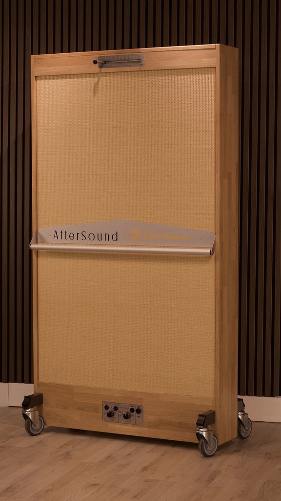 Reverbophone in a honey oak frame with a blond grille, standing on castors against a slatted timber wall