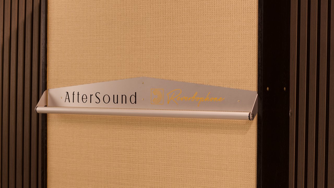 The brushed aluminium AfterSound and Reverbophone sign and handle rail mounted across a blond grille weave.